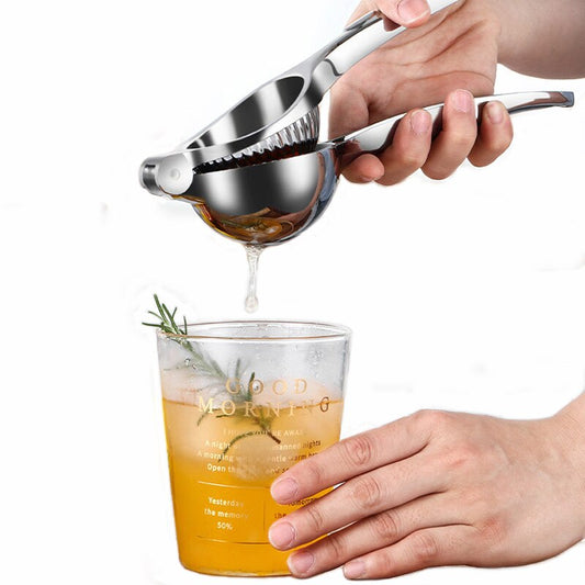 Frucht-Presse wird mit einer Hand betätigt und Saft strömt aus in ein Glas Tee | Zitronen / Orangen-Presse Edelstahl Entsafter Qualität und Design